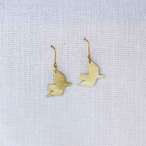 Gold bird-shaped earrings on a light gray fabric background