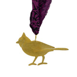 Gold bird ornament with a purple feather on a white background