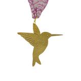 Gold hummingbird ornament with pink and white patterned ribbon on a white background