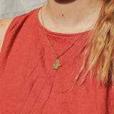 Person wearing a gold necklace with a bird pendant on a red shirt.