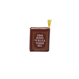 A miniature book-shaped ornament or bookmark with a dark reddish-brown cover, gold decorative border details, and a yellow ribbon bookmark coming out from the top. The front cover features the text 'ONE RING TO RULE THEM ALL' in white lettering.