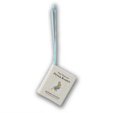 A Peter Rabbit book-shaped ornament or small hanging book with a light blue ribbon loop, shown on a plain white background.
