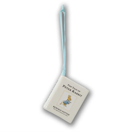 A Peter Rabbit book-shaped ornament or small hanging book with a light blue ribbon loop, shown on a plain white background.
