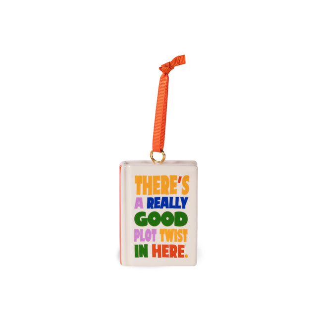 A square white ornament with a colorful text print reading 'THERE'S A REALLY GOOD PLOT TWIST IN HERE.' and an orange hanging ribbon, shown on a plain white background.