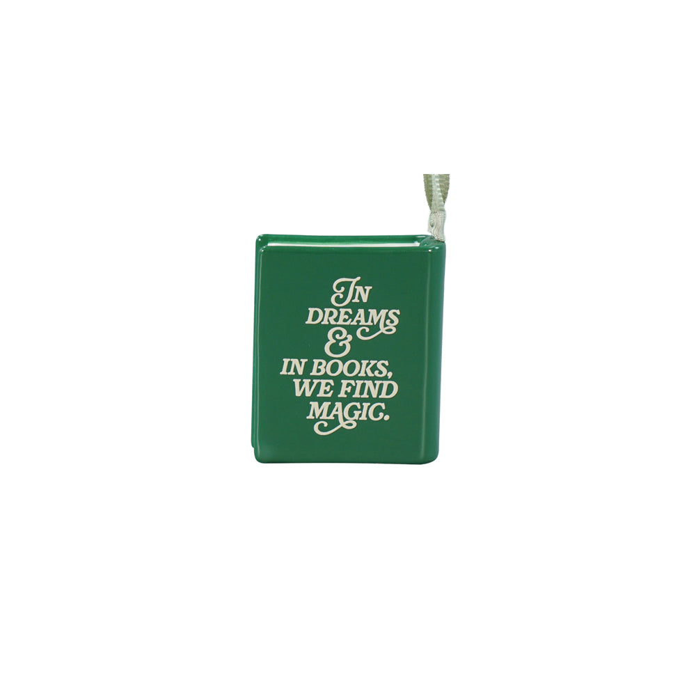 A small green book-shaped hanging decoration with white text reading 'In Dreams & In Books, We Find Magic.' on a plain white background.
