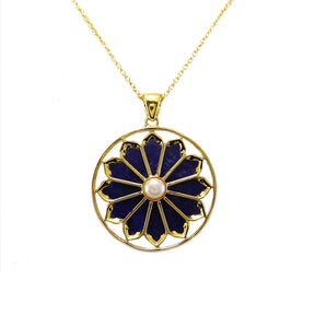 A gold plated necklace with a floral pendant featuring lapis and a pearl.